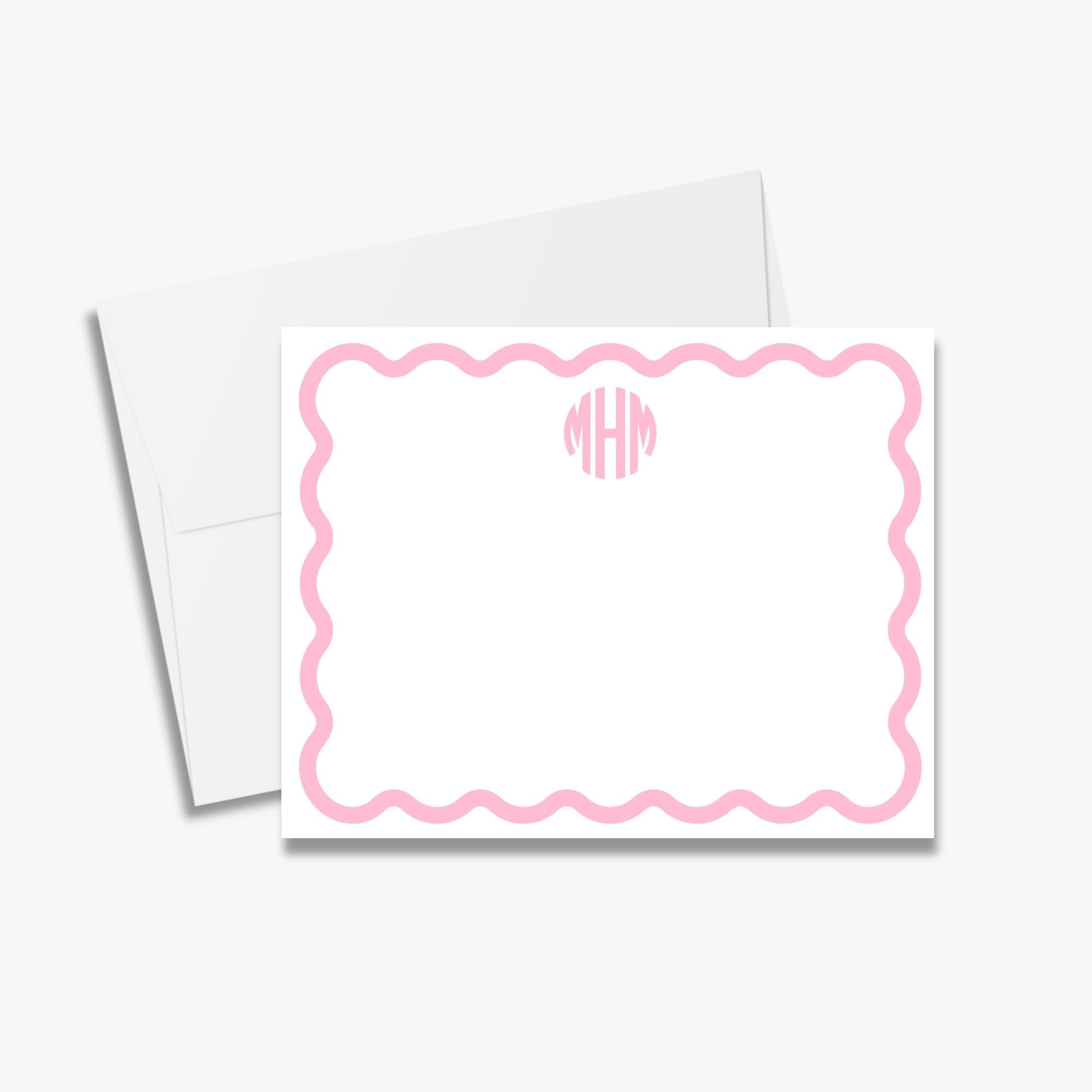 a white envelope with a pink scalloped border and a pink wavy border, along with a blank card inside.