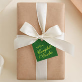 A gift wrapped in brown paper with a white ribbon and a green tag that reads "a gift from Campbell & Corales".