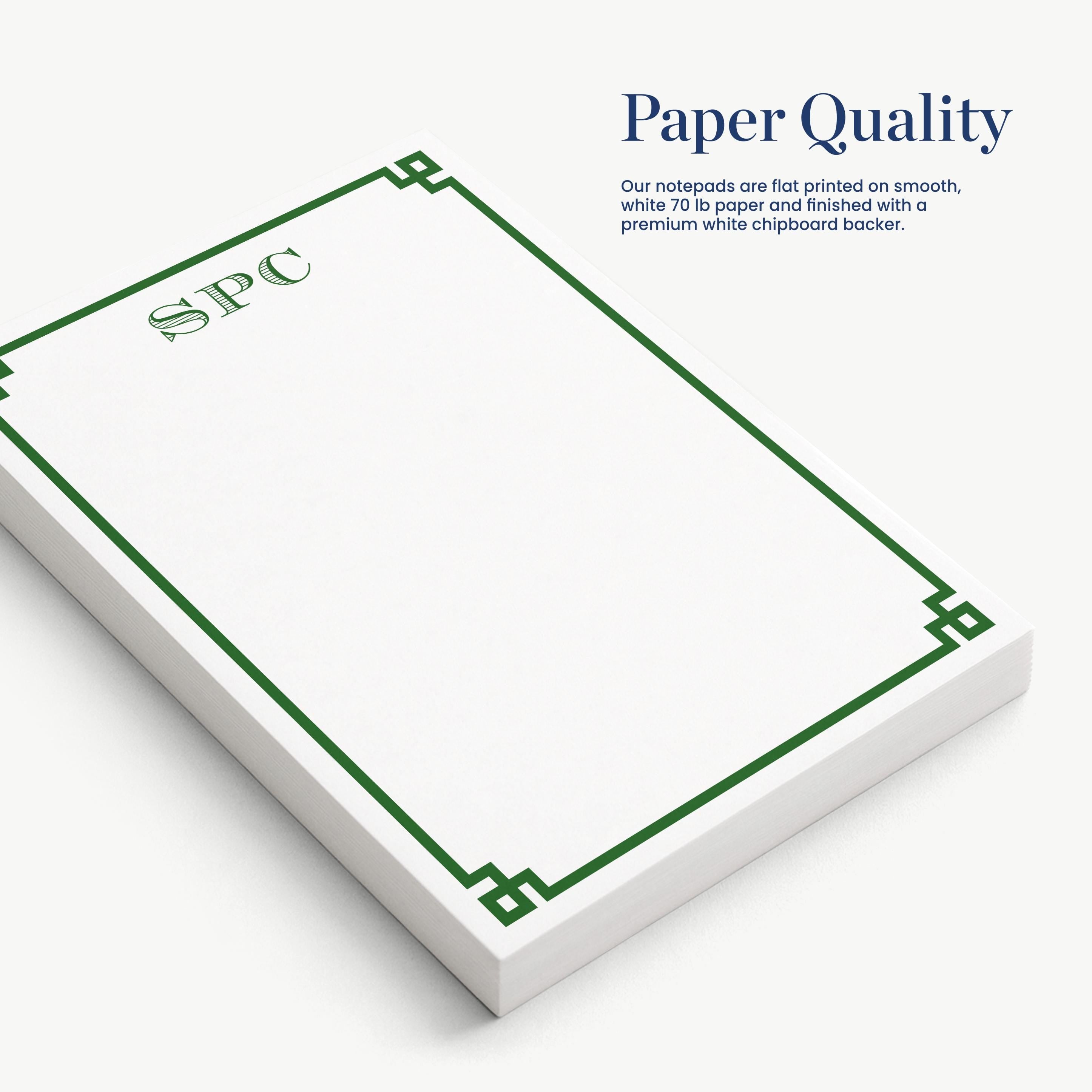 a set of white notepads with a green border, arranged on a white surface.