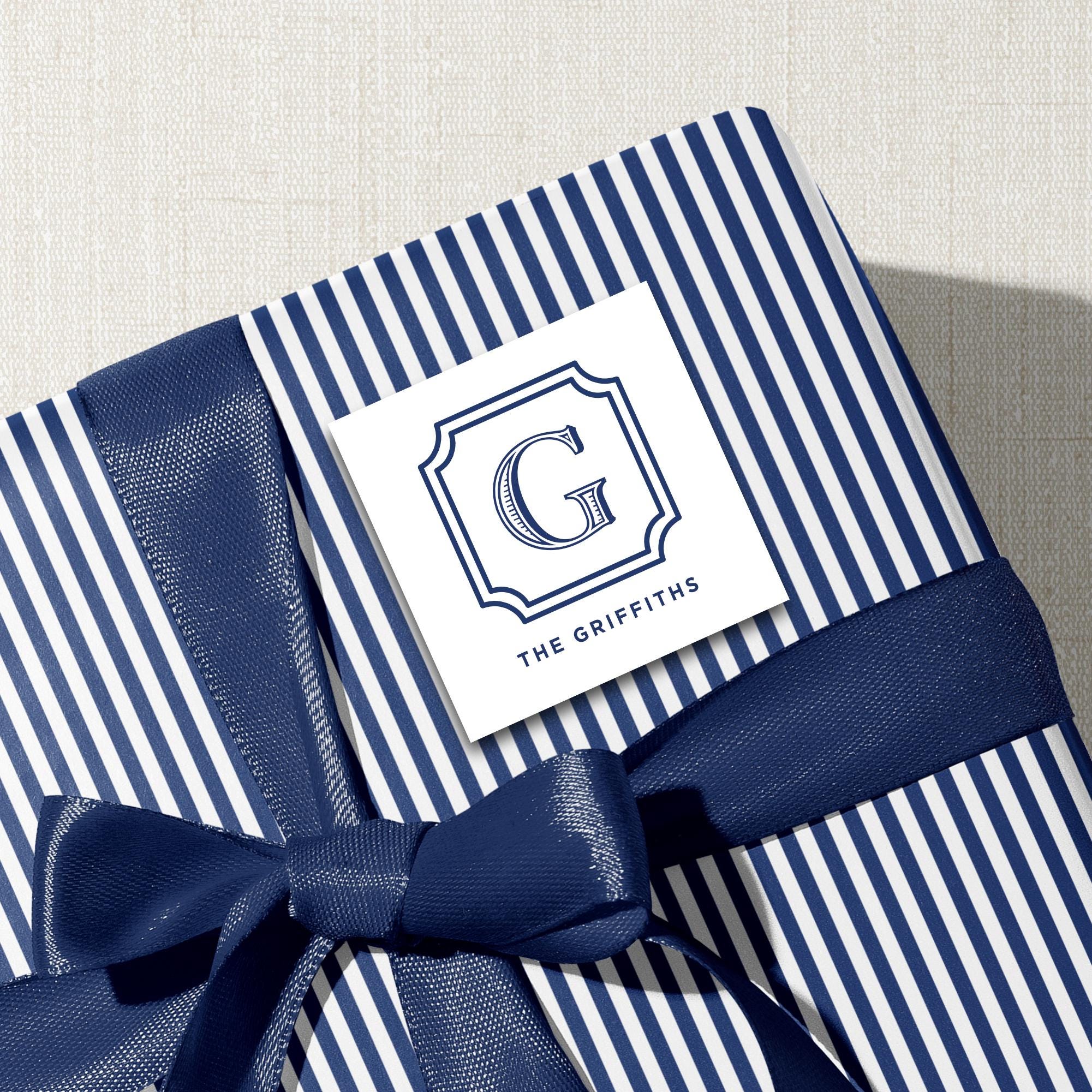 A blue and white striped gift box with a blue ribbon tied around it, and a white label with the text "The Griffiths" printed on it.