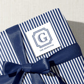A blue and white striped gift box with a blue ribbon tied around it, and a white label with the text "The Griffiths" printed on it.