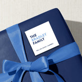 A blue gift box with a blue ribbon tied around it, featuring a white label with the text "THE BRADLEY FAMILY WILL CECIL OLIVIA & CAMBRELL" printed on it.
