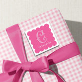 A pink ribbon-wrapped gift box with a pink scalloped label featuring the name 'CATHERINE' on it.