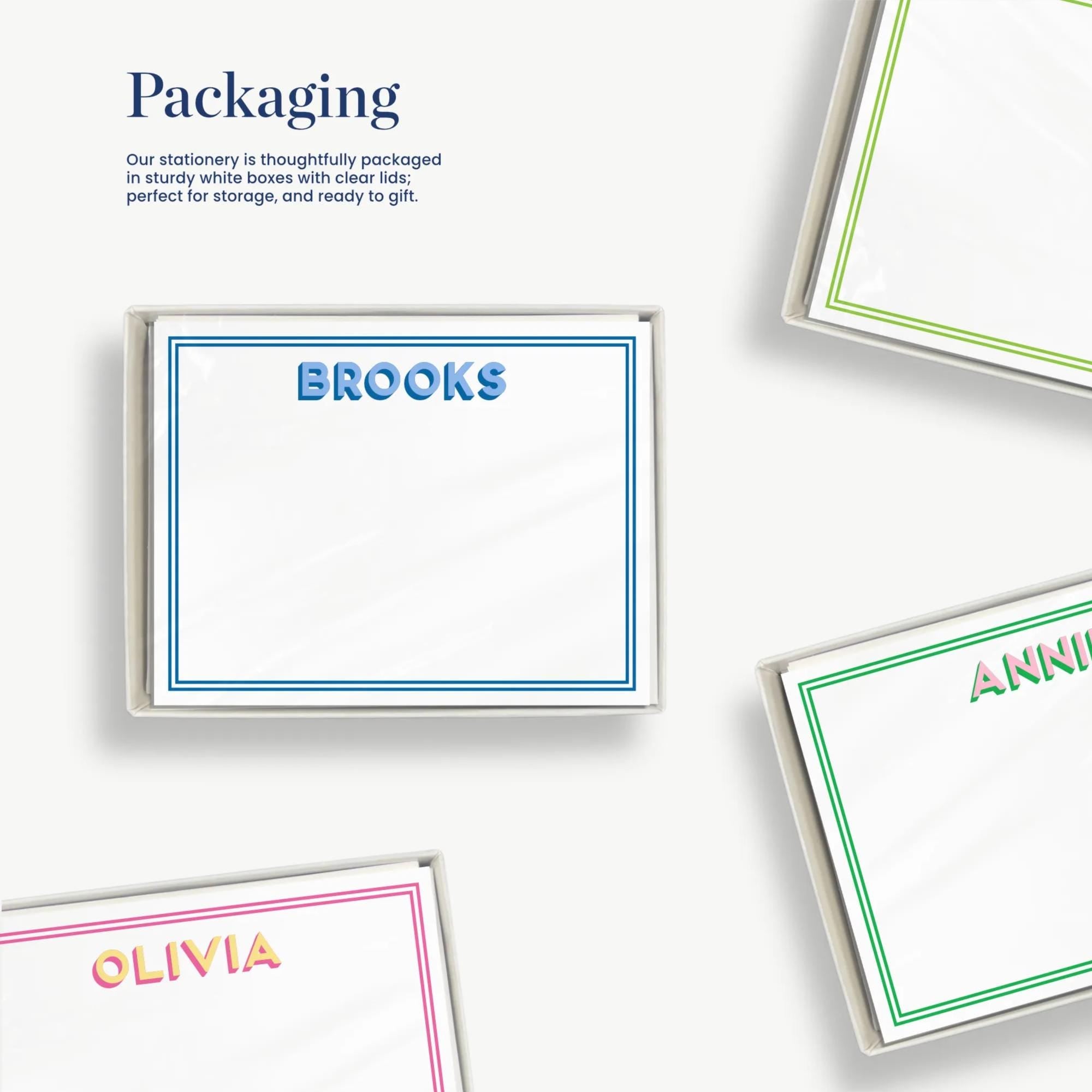 several blank name cards with personalized names on them, along with some other items such as a green and white box and a pink and white box. The cards are arranged in a way that suggests they are being packaged for gift purposes.