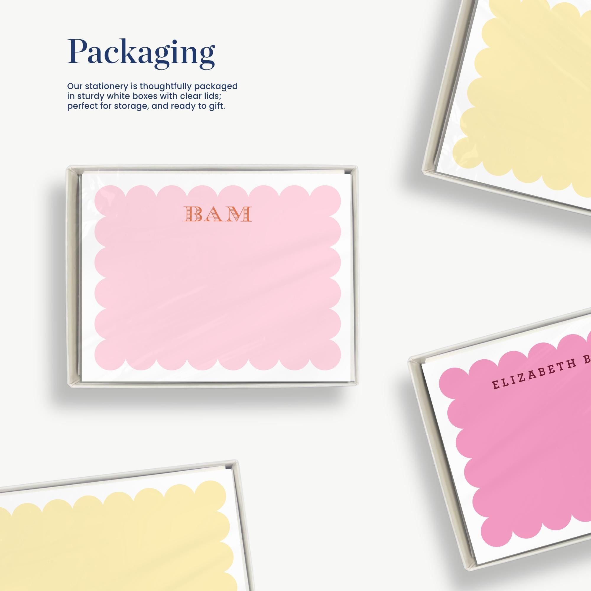 a set of stationery items, including a pink card with a scalloped edge and a yellow card with a scalloped edge, all neatly arranged in a box.