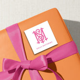 a gift box with a pink ribbon and a white label with a pink monogram.