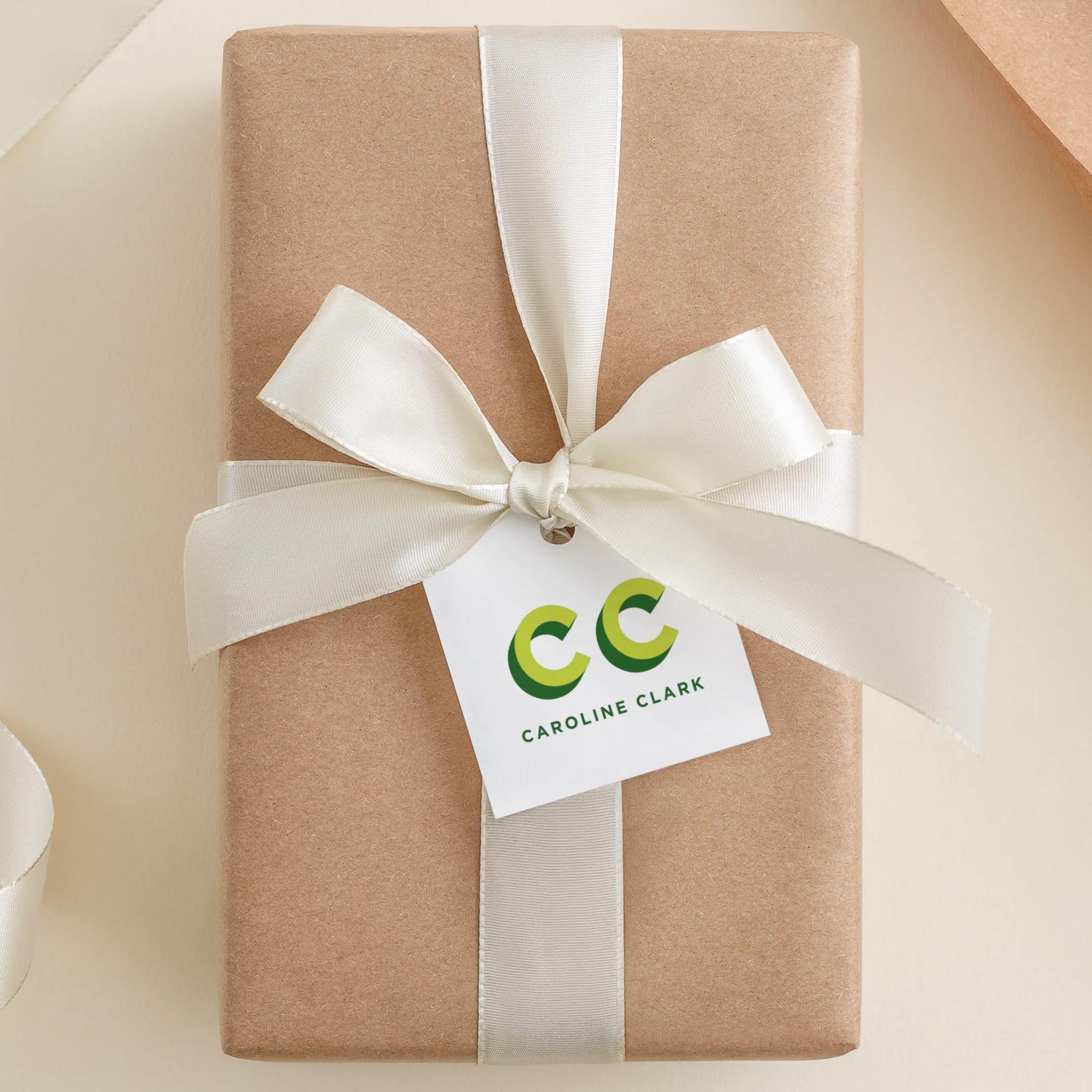 A gift box wrapped in brown paper with a white ribbon and a tag that reads "CC Caroline Clark".