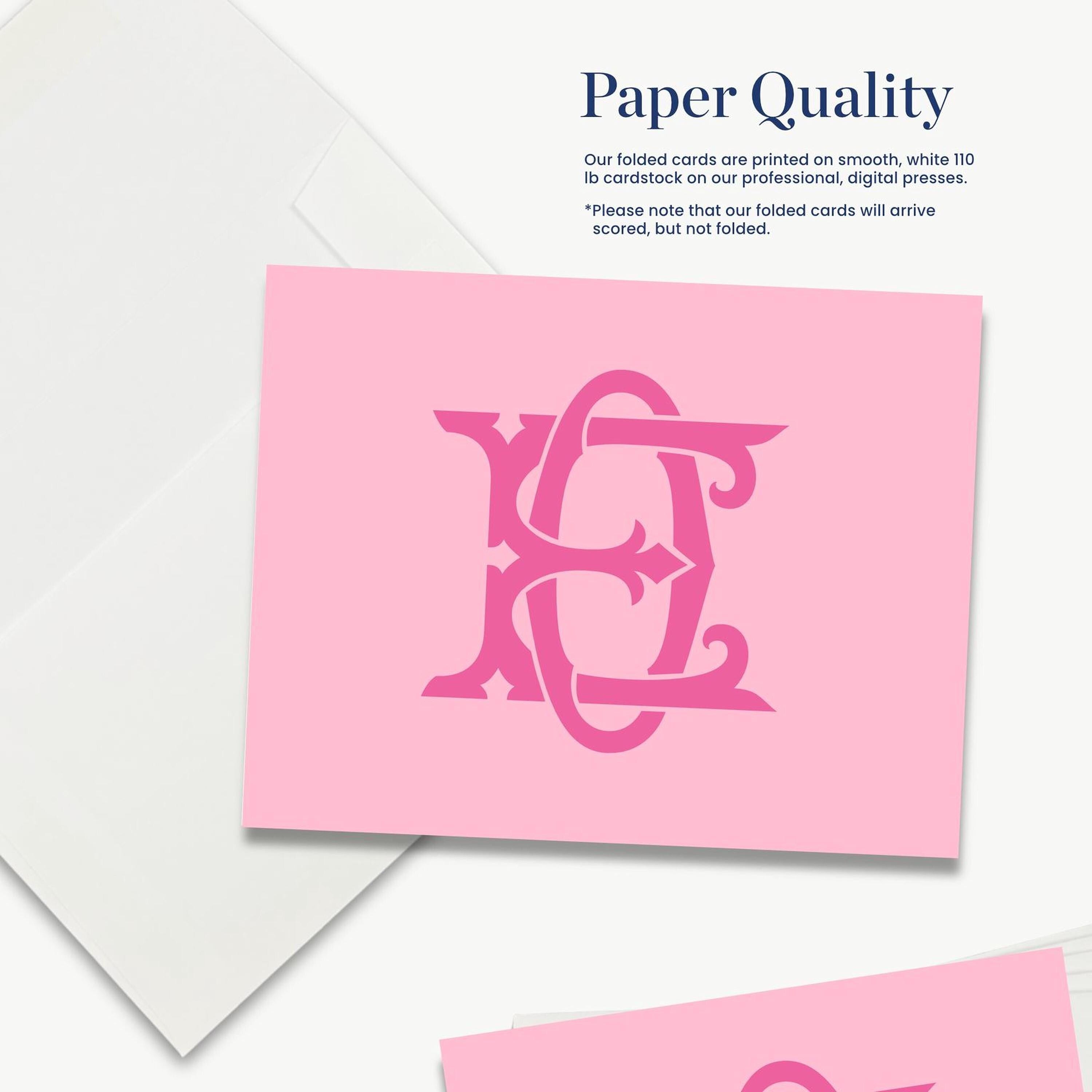a pink card with a stylized monogram design, and there is a white card with text next to it.