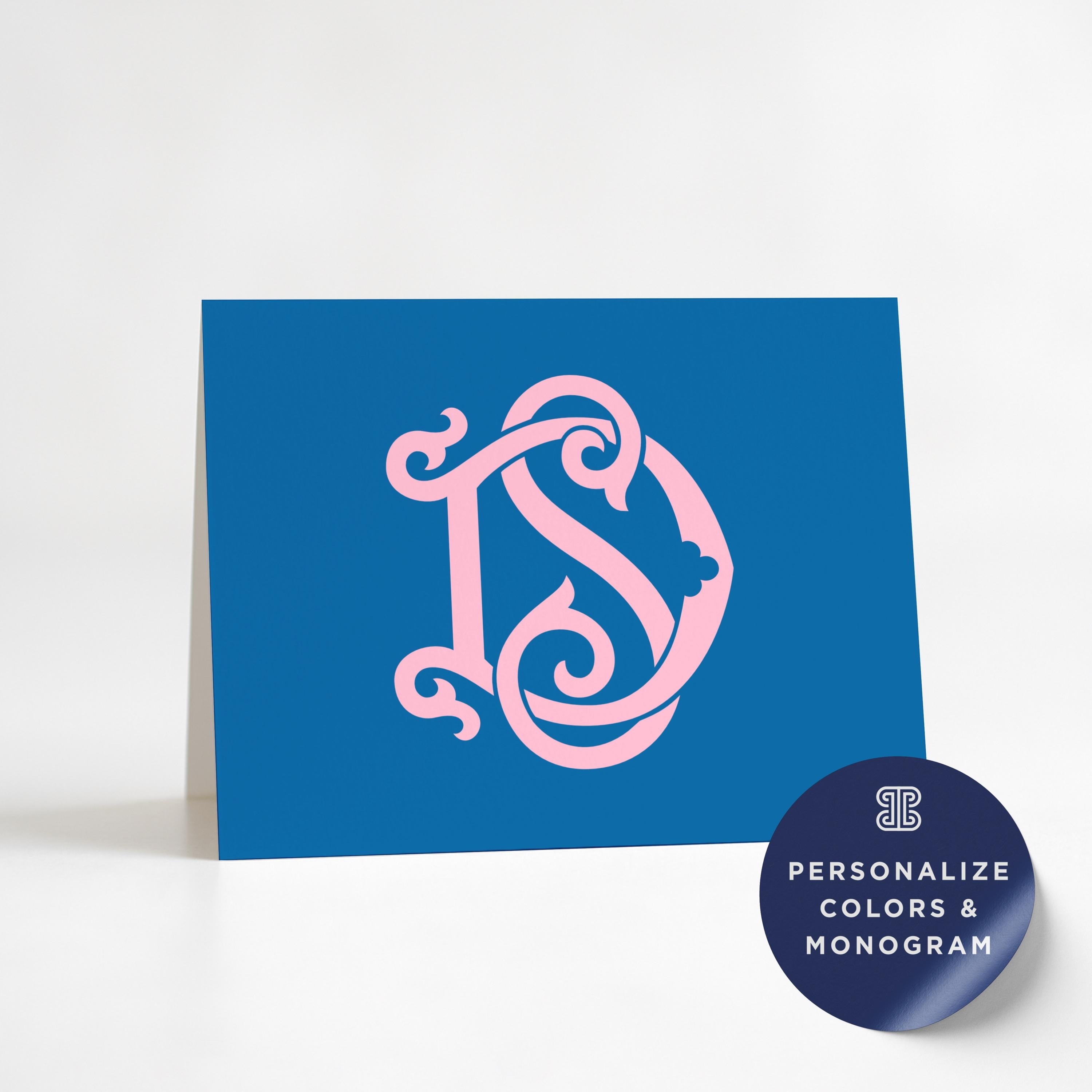 A blue greeting card with a pink monogram design on it, and a round sticker with the text "Personalize Colors & Monogram" on it.