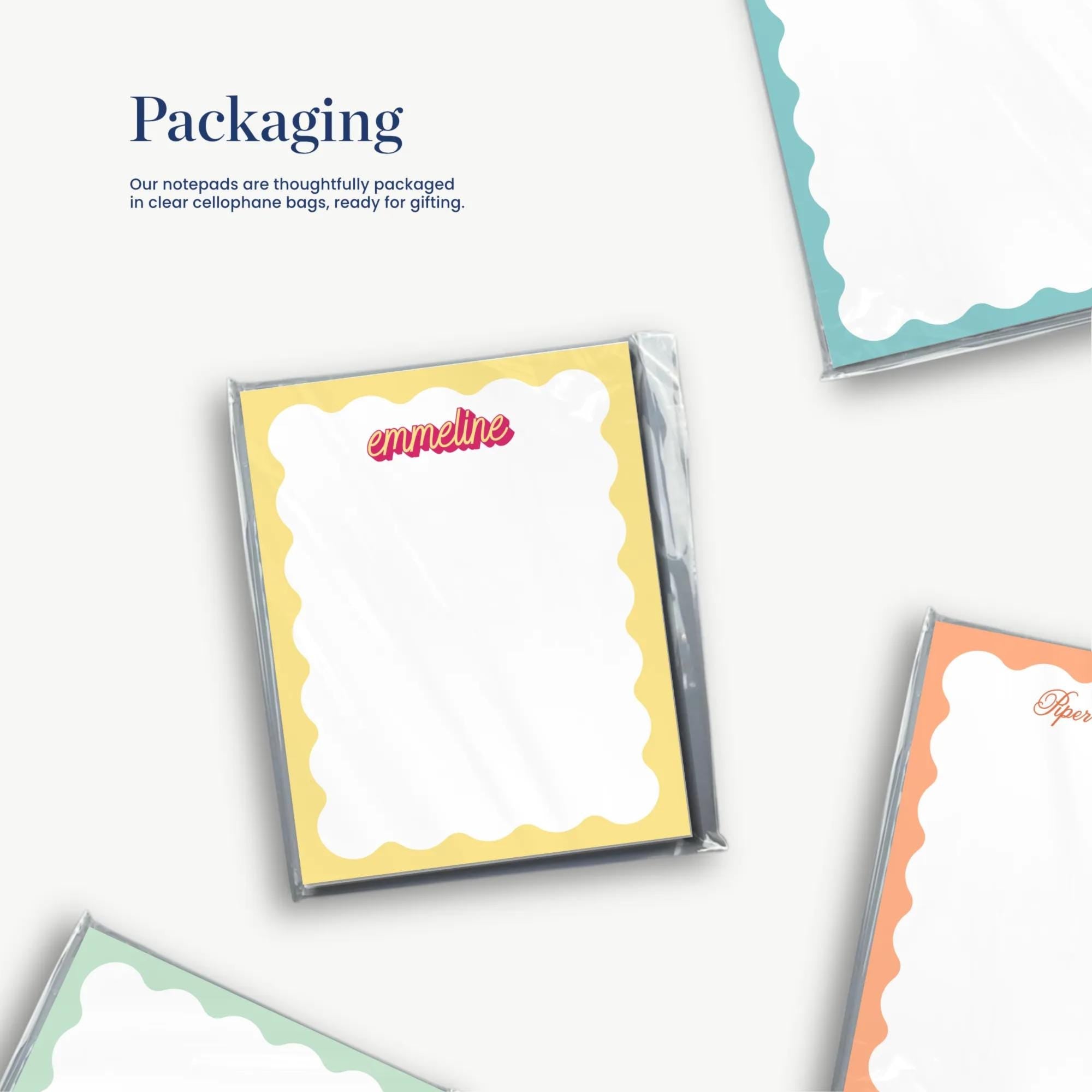 three different colored notepads with scalloped edges, arranged on a white background.