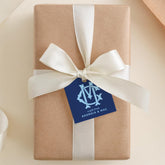 A brown gift box with a white ribbon and a blue tag that reads "A gift from GEORGIA & MAC".