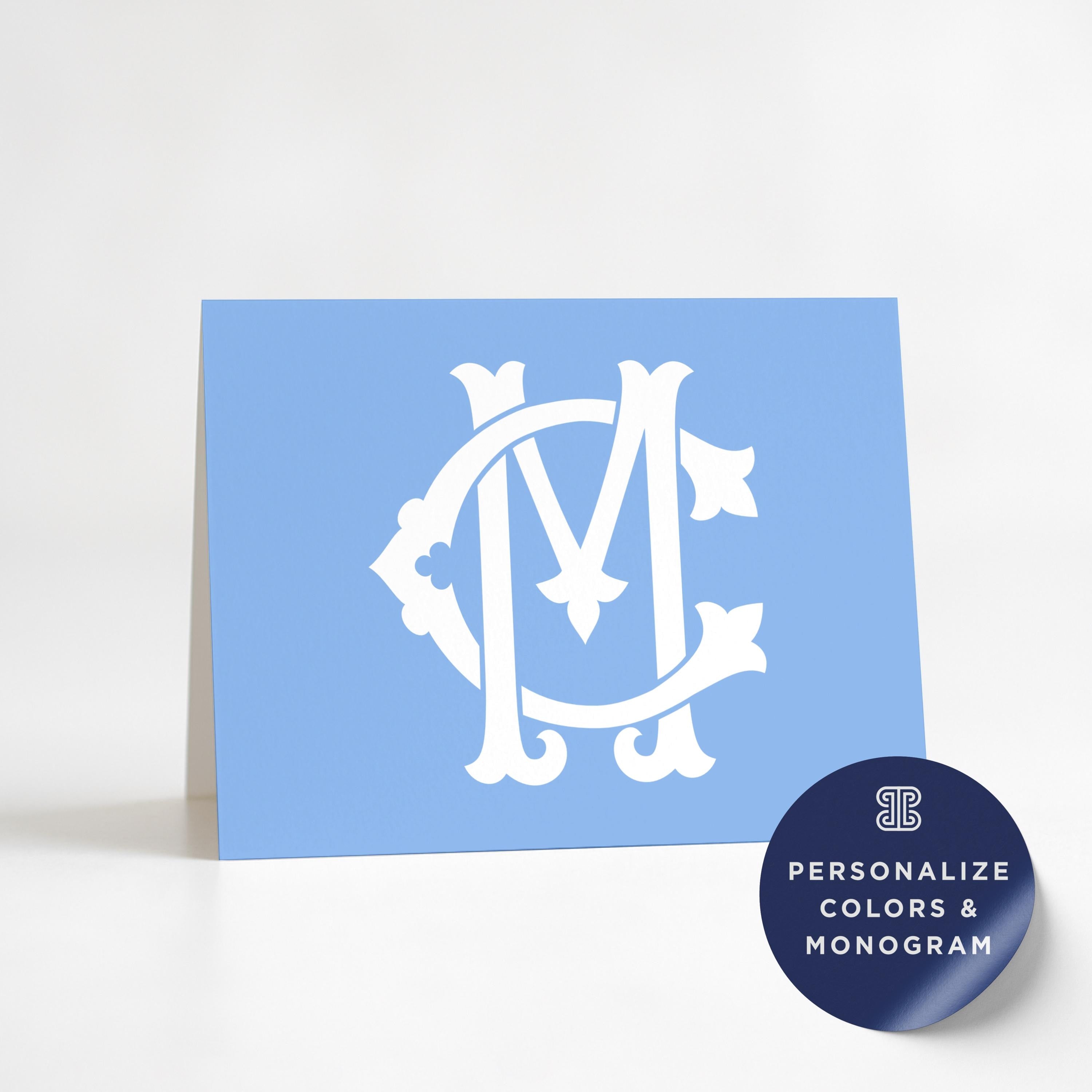 A blue greeting card with a white monogram logo on it, along with a round sticker that says "Personalize Colors & Monogram".