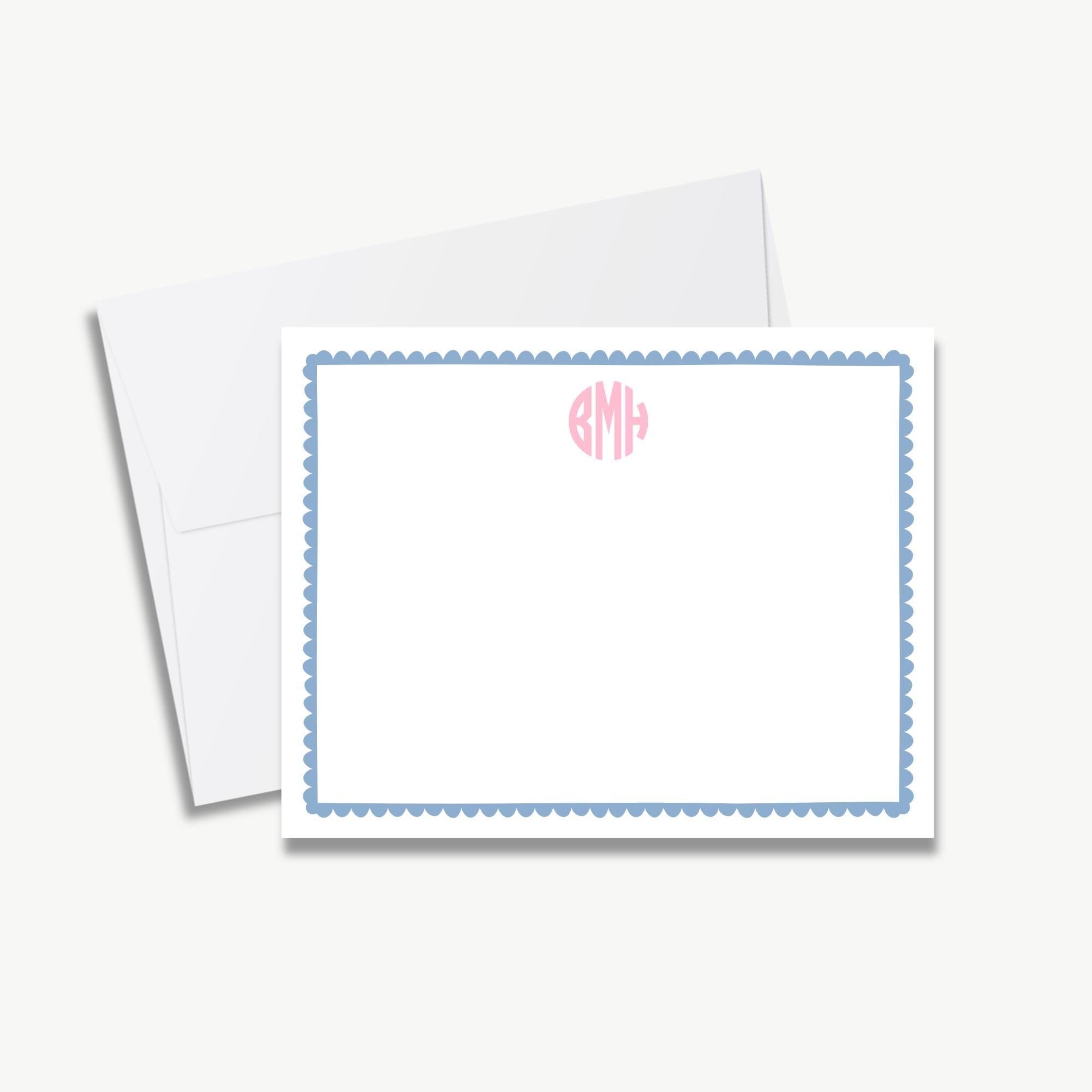 a white card with a blue border and scalloped edges, placed on top of an envelope.