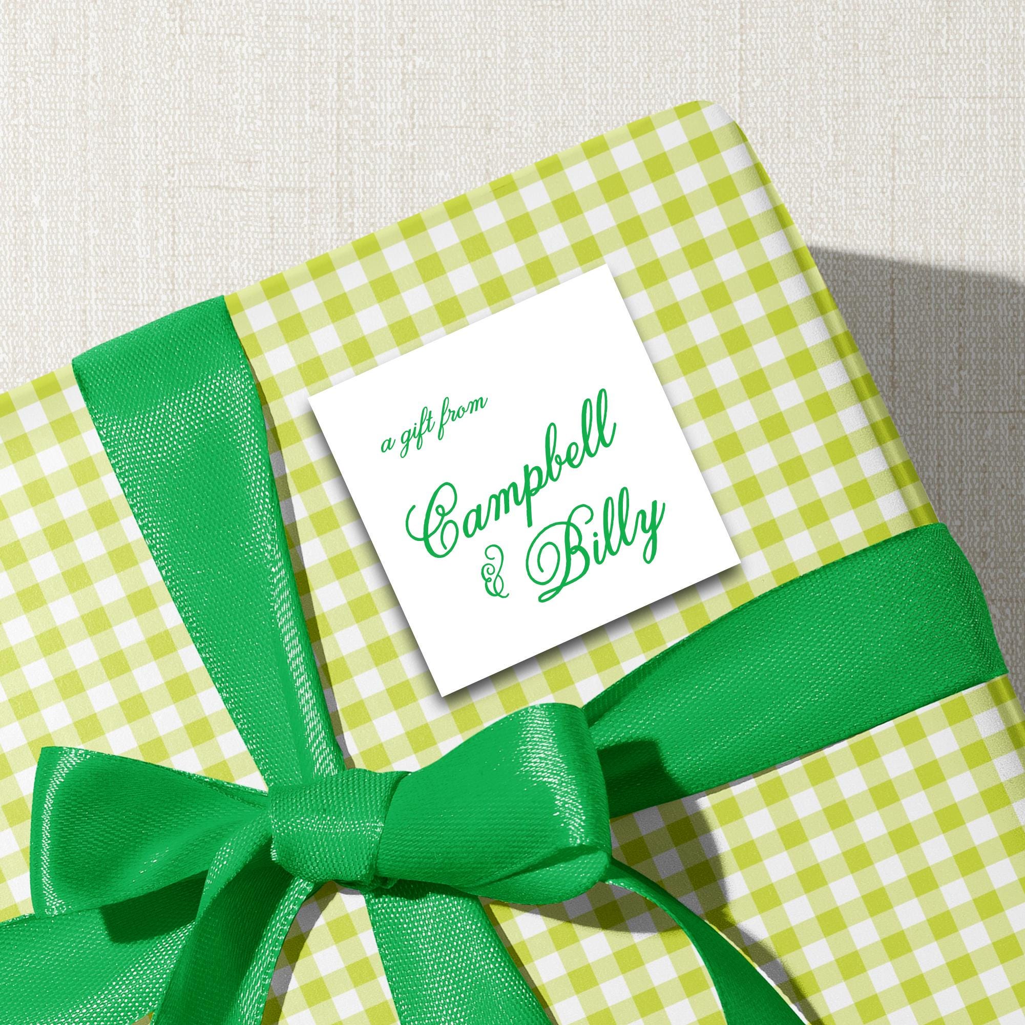 A gift wrapped in a green and white checkered paper with a green ribbon tied around it, featuring a white label with the text "a gift from Campbell & Billy".