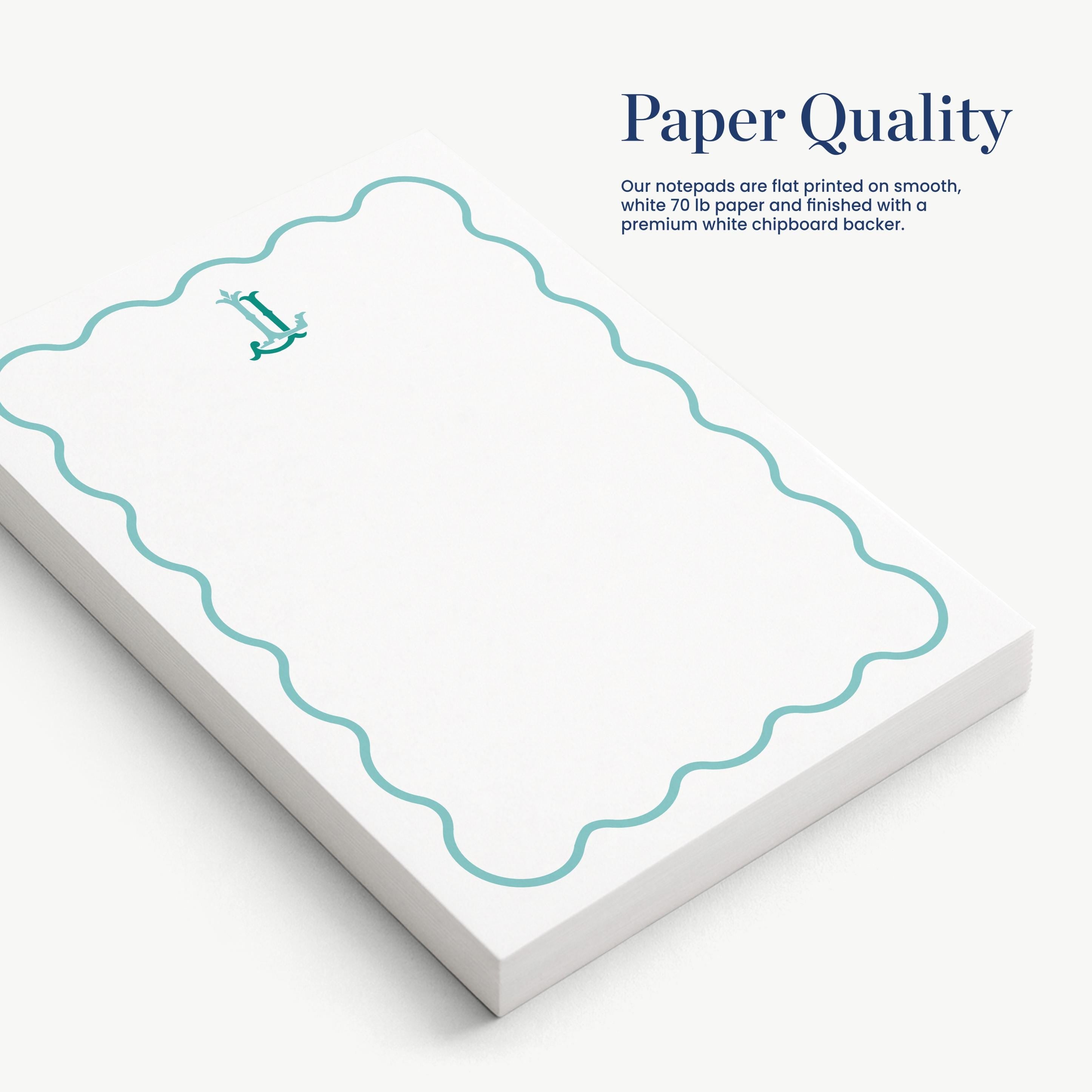 a set of white notepads with a scalloped edge and a small green logo on the top left corner.