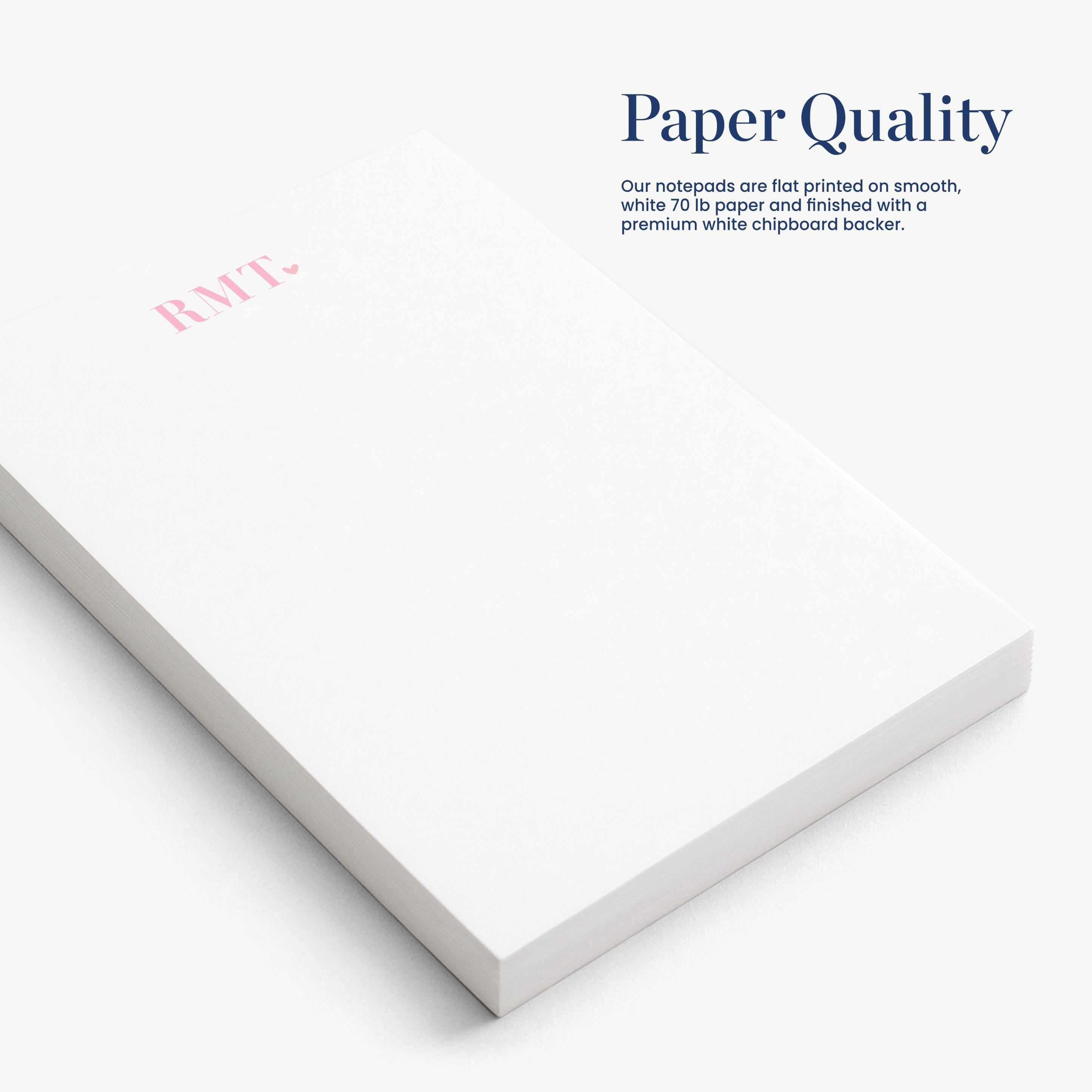 a close-up view of a white notepad with a pink logo on it, placed on a white surface.