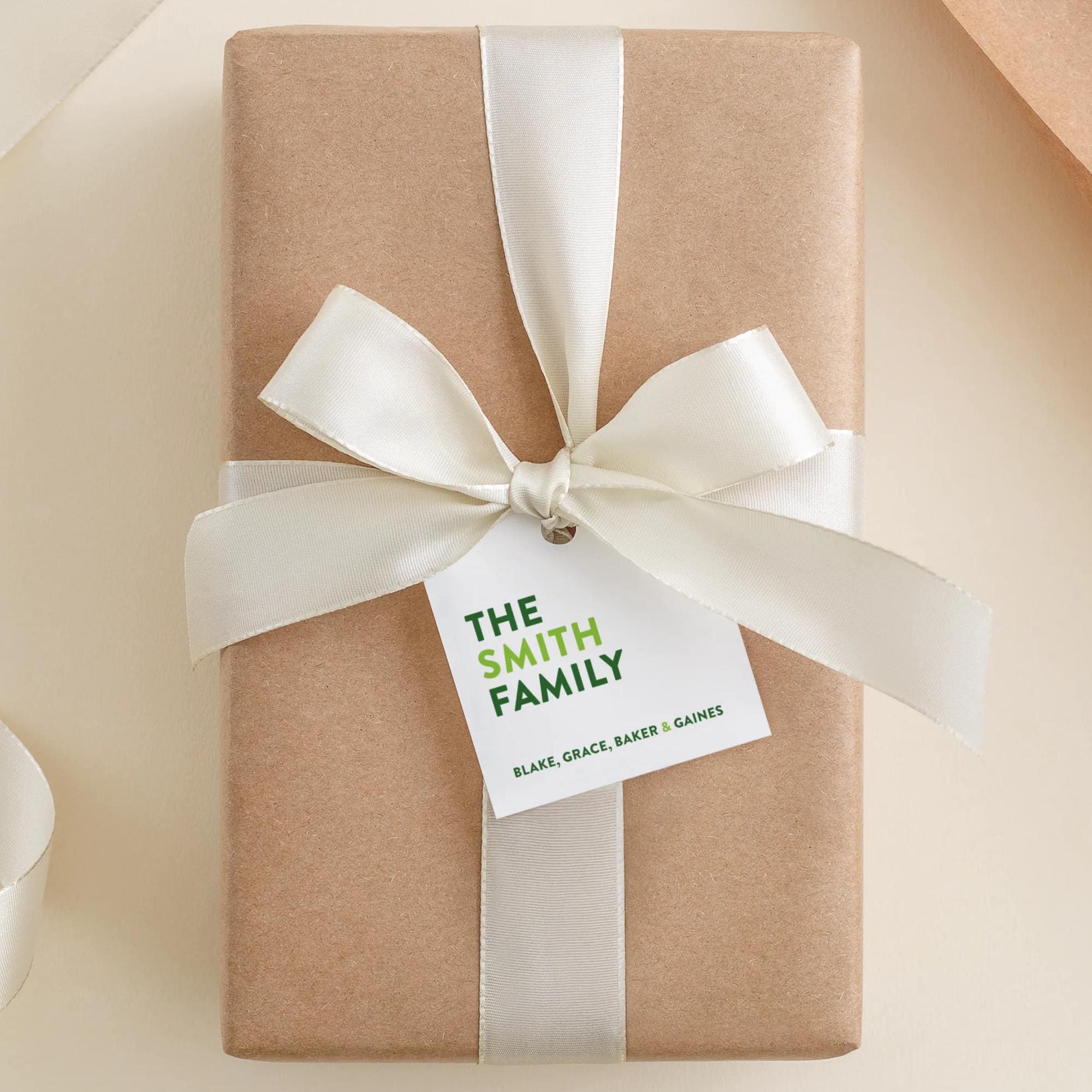 A brown gift box with a white ribbon and a tag that reads "THE SMITH FAMILY BLAKE, GRACE, BAKER & GIANES".