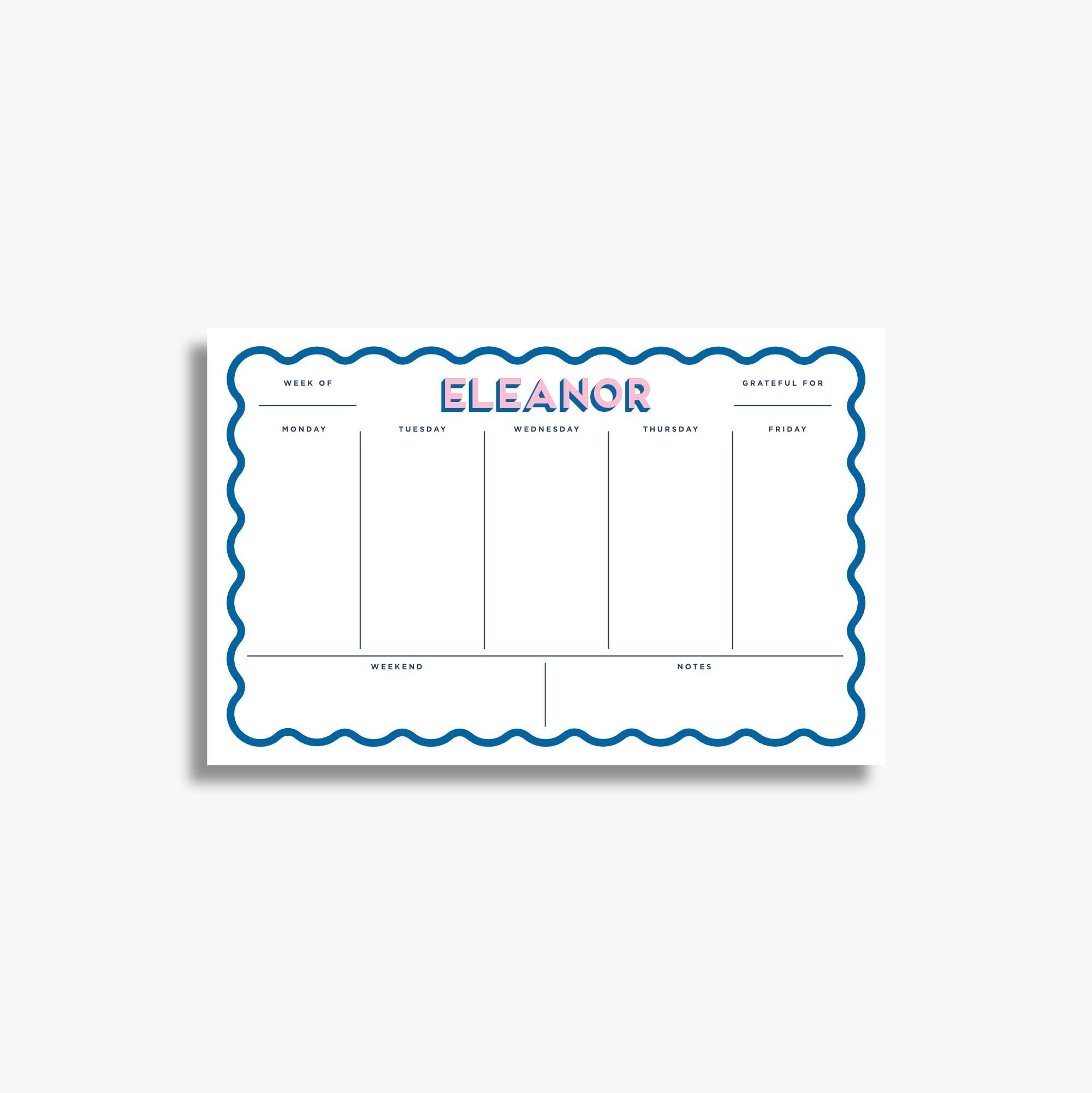 A white schedule planner with the name "ELEANOR" written in large blue letters. The planner has a scalloped edge and is divided into sections for each day of the week, with blank spaces for notes.